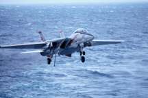 a military jet fighter, f-14, lands on the uss kitty hawk