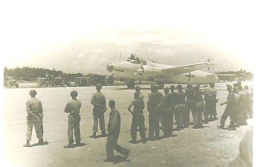 Soldiers line up as the Betty Bomber taxis in on the island of Ie Shima WW2