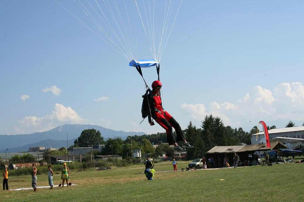 Diana is almost on the ground as people watch her parachute landing proceedure