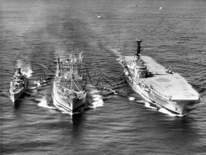 An aerial shot of three British Royal Navy ships while refueling, one of them is a Brittish Aircraft Carrier
